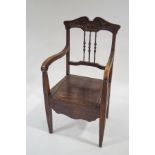 An Edwardian beech commode armchair with carved cresting rail and turned spindles