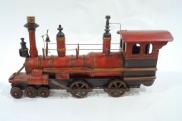 An early 20th Century model of a steam train with turned and painted body on cast iron wheels and