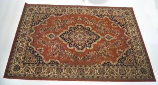 A large modern Persian style carpet, with central medallion upon a terracotta ground,