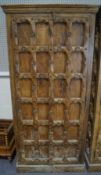 An Indian hardwood cupboard, the doors carved with gridwork and rosettes,