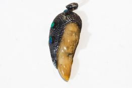 An opal, bone and white metal mounted pendant, carved as the face of a female,