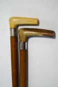 A pair of malacca walking sticks with silver bands and horn handles