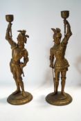 A pair of brass candlesticks modelled as knights wearing winged helmets,