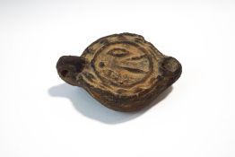 A Roman earthern ware oil lamp with moulded decoration,