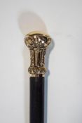 A slim walking cane with intricate gilt top