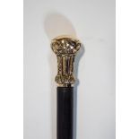 A slim walking cane with intricate gilt top