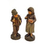 A pair of 19th century German terracotta figures of peasant children eating,