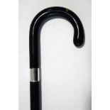 An ebonised walking stick with wide silver band