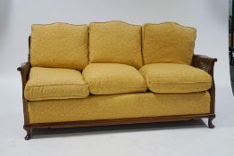 A 20th century beech framed three seat bergere sofa, with patterned upholstery,