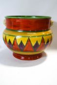An early Clarice Cliff Jardiniere with two mask handles, painted with a geometric design,