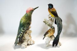 Two Karl Ens figures of a Green Woodpecker, 23cm high and a pair of exotic birds,