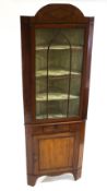A George III mahogany standing corner cupboard with one glazed door above a short drawer and