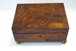 A Victorian walnut work box with compartmental interior, raised on ball feet,