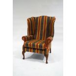 A George III style wingback armchair, upholstered in striped and patterned fabric,