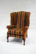 A George III style wingback armchair, upholstered in striped and patterned fabric,