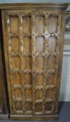 An Indian hardwood cupboard, the doors carved with gridwork and rosettes,