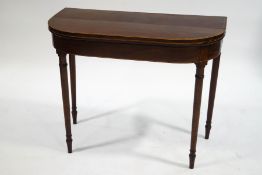 A George III mahogany card table with satinwood stringing on turned tapering legs,