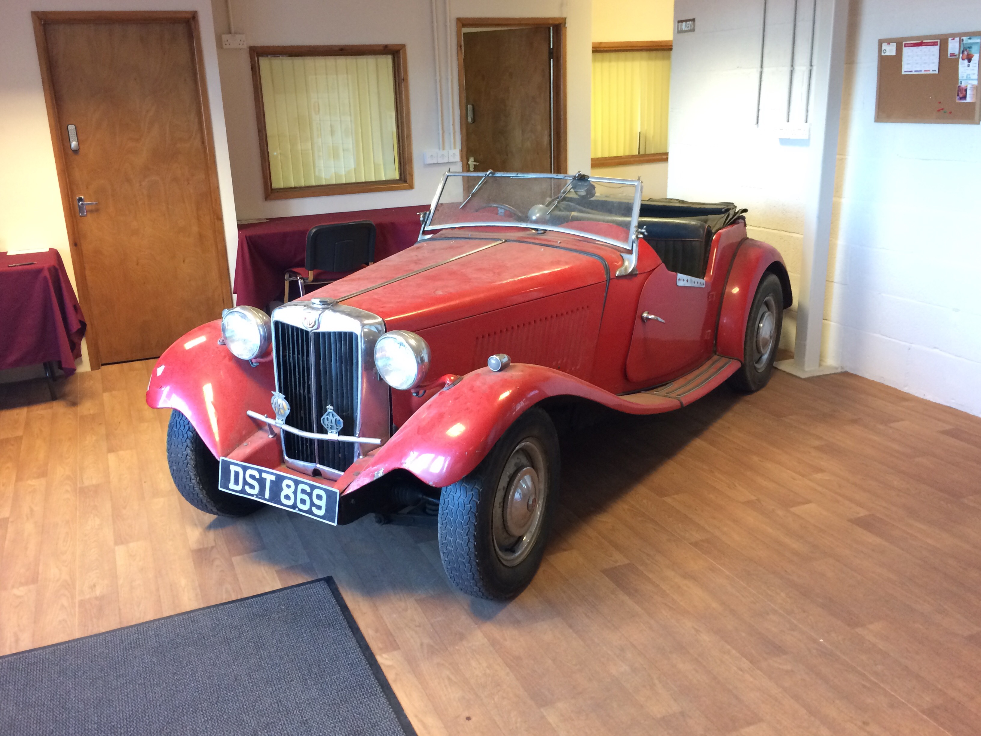 A 1950 MGTD Special, registration number DST 869, red.