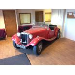 A 1950 MGTD Special, registration number DST 869, red.