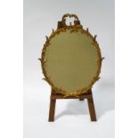 A gilt frame oval wall mirror, with a scrolling foliage surround,