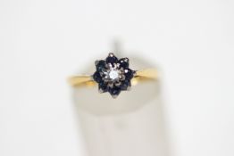 An 18 carat gold diamond and sapphire cluster ring, the central diamond of approximately 0.