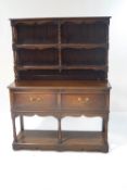 An 18th century style oak dresser, with raised back and turned supports to the shelves,