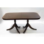A reproduction mahogany twin pedestal dining table with two leaves,