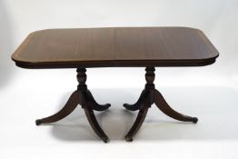 A reproduction mahogany twin pedestal dining table with two leaves,