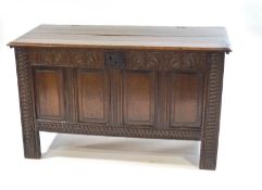 An 18th century oak coffer with carved and panel front and sides,