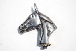 A metal car mascot, in the form of a horse's head,