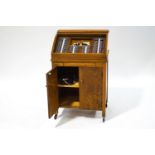 An oak opticians cabinet with tambour front opening to reveal various lenses,