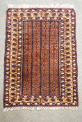 A Middle Eastern rug with geometric repeating design on a red ground,
