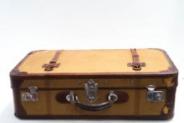 A vintage leather bound canvas suitcase, with pale blue interior,