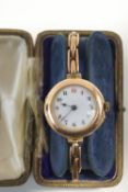 A 9 carat gold lady's wristwatch, with an enamel dial, on an expanding baton link bracelet,