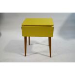 A vintage yellow formica kitchen table with drop ends on tapering legs, 75cm high x 89cm wide x 60.