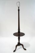 A mahogany standard lamp with circular shelf on cabriole legs and ball and claw feet,