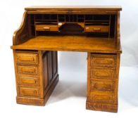 An oak roll top desk with tambour front with one frieze drawer and four drawers to each pedestal,