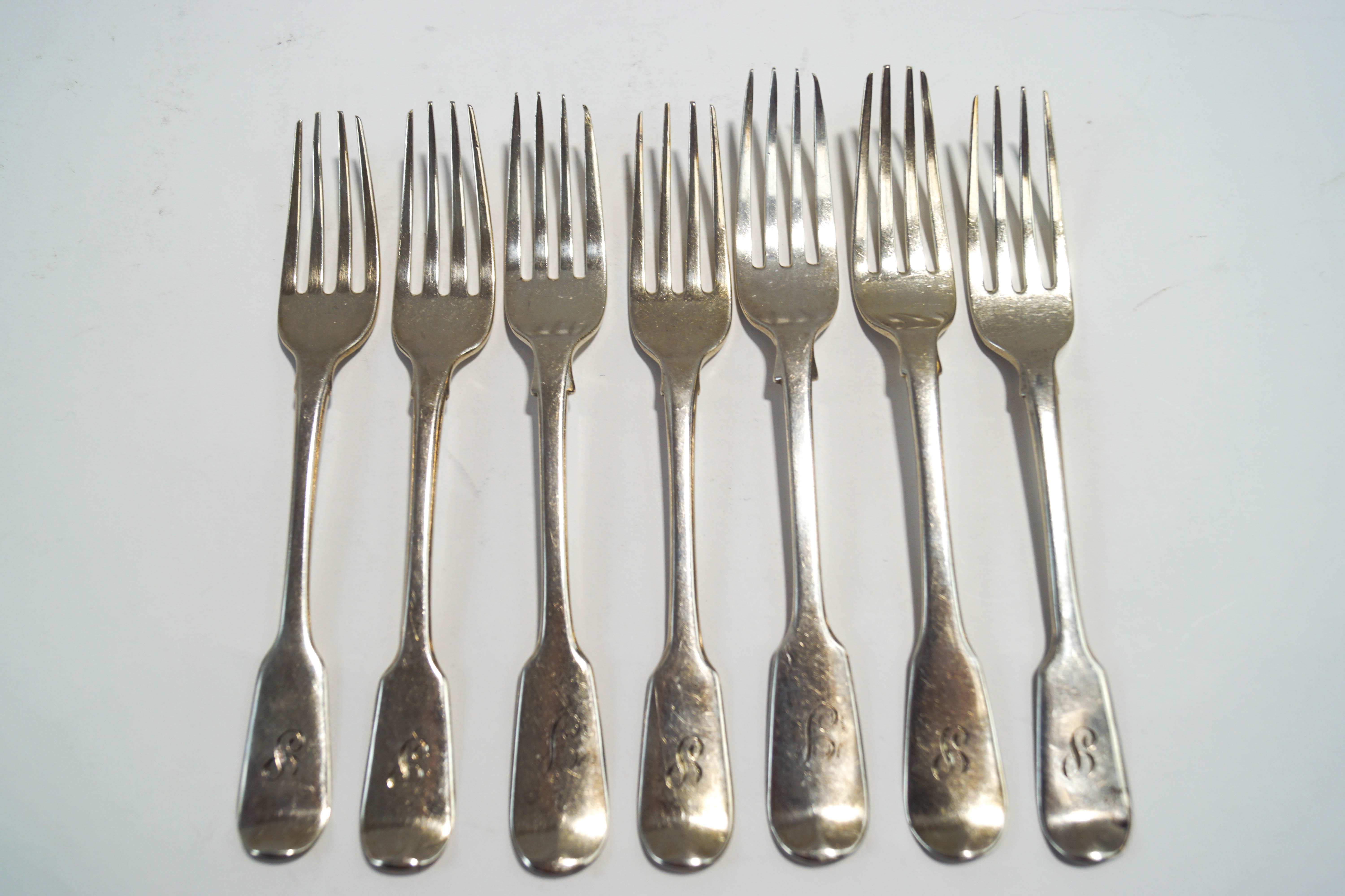 A matched set of seven antique silver dessert forks, various makers and dates, fiddle pattern,
