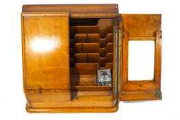 An oak stationery box, the two doors opening to reveal various sections and a drawer,