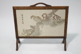 A Chinese silk work picture of a bird perched on a branch, within an oak fire screen frame,