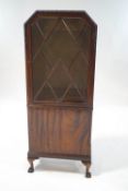 A mahogany display cabinet with glazed doors above one cupboard door,