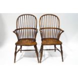 A pair of 19th century beech and elm comb back Windsor chairs, each with a saddle seat,