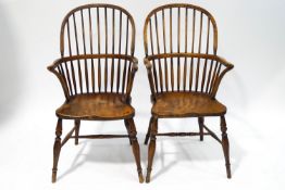 A pair of 19th century beech and elm comb back Windsor chairs, each with a saddle seat,