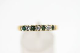 An emerald and diamond seven stone 18 carat gold half eternity ring,