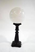 A patinated aluminium table lamp base with globular glass shade,