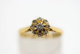 A diamond cluster ring, stamped '18ct Plat', the central brilliant cut enclosed by single cuts,