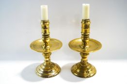 A pair of late 17th/early 18th century bronze candlesticks with drip pans and flared bases,