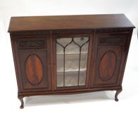 A mahogany display cabinet with one glazed door flanked by two panelled and carved doors on