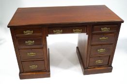 An Edwardian mahogany kneehole desk with brass aesthetic movement style handles,