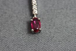 A ruby and diamond pendant, the oval cut to a baton of five small brilliant cuts,
